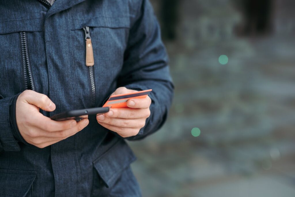 Man holding a credit card and a smartphone on the street.